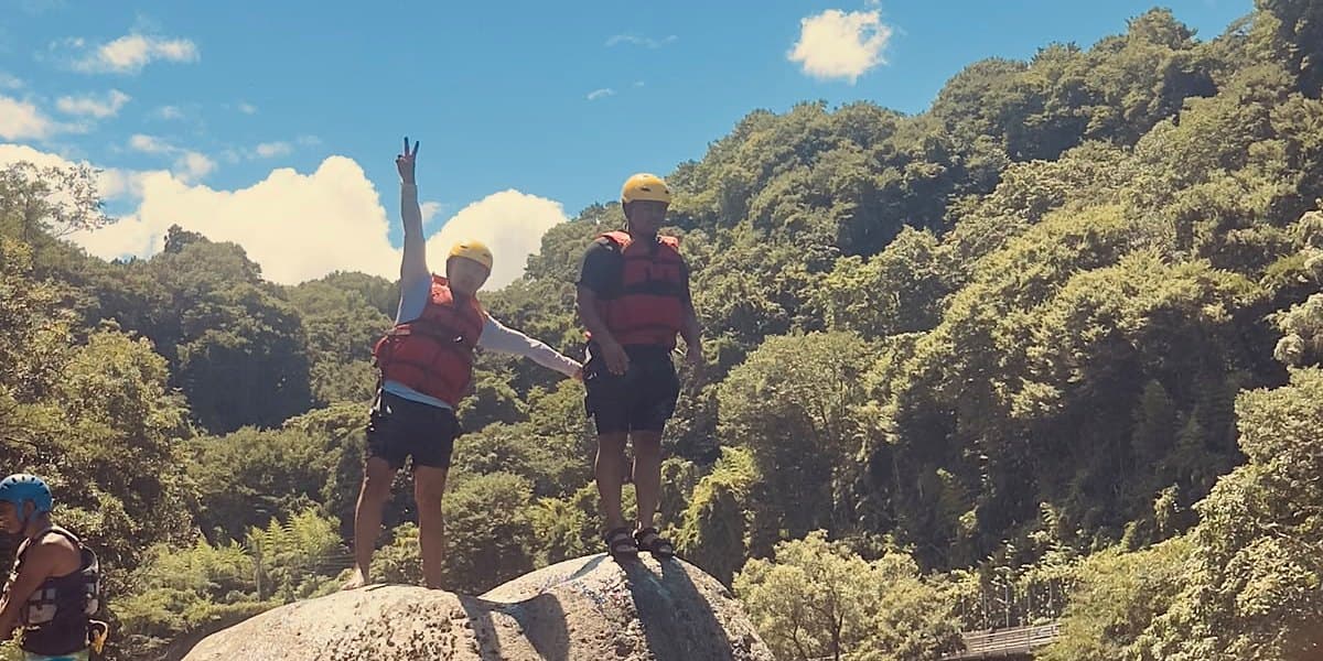 Guests standing on a boulder in a Gunma gorge, arms raised